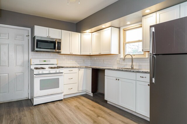 kitchen with stainless steel appliances, white cabinetry, a sink, and tasteful backsplash