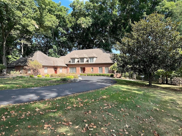 view of front of home featuring driveway, a front lawn, and brick siding