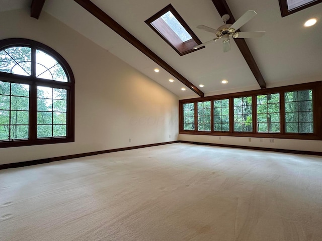 empty room featuring a skylight, light carpet, high vaulted ceiling, beamed ceiling, and baseboards