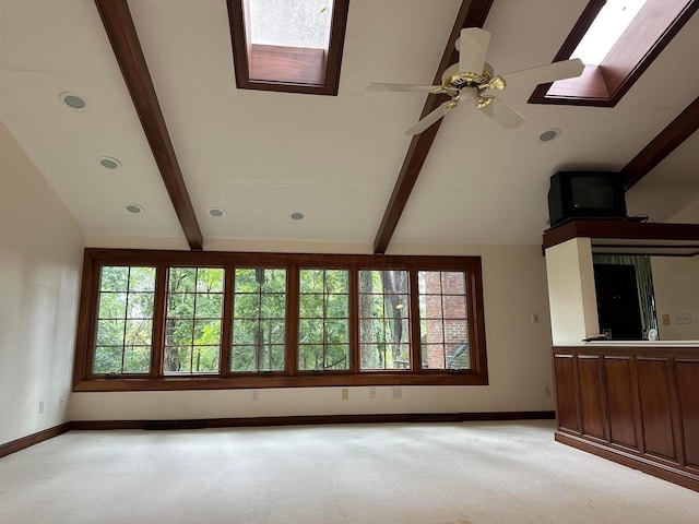 interior space with baseboards, vaulted ceiling with skylight, and a healthy amount of sunlight