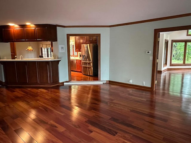 interior space featuring dark wood-style floors, baseboards, appliances with stainless steel finishes, and crown molding