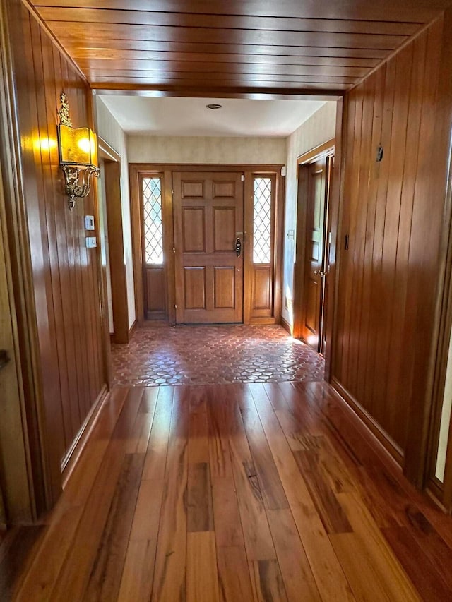 foyer entrance featuring wooden ceiling, wood walls, and wood-type flooring