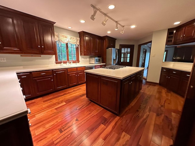 kitchen with a sink, appliances with stainless steel finishes, light countertops, and wood finished floors