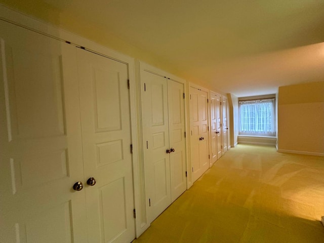 hall with baseboards and light colored carpet