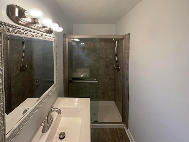 bathroom featuring a shower stall, baseboards, and wood finished floors