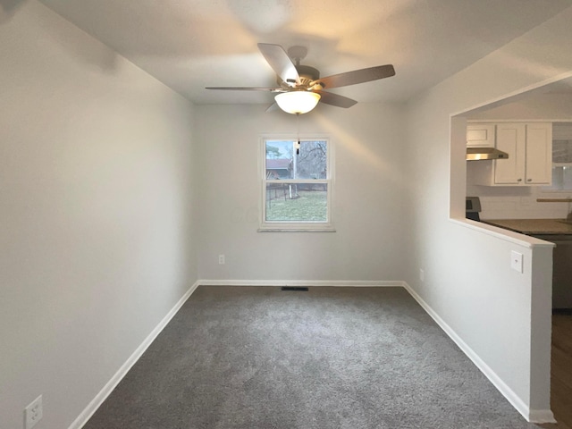 empty room featuring ceiling fan, dark colored carpet, visible vents, and baseboards