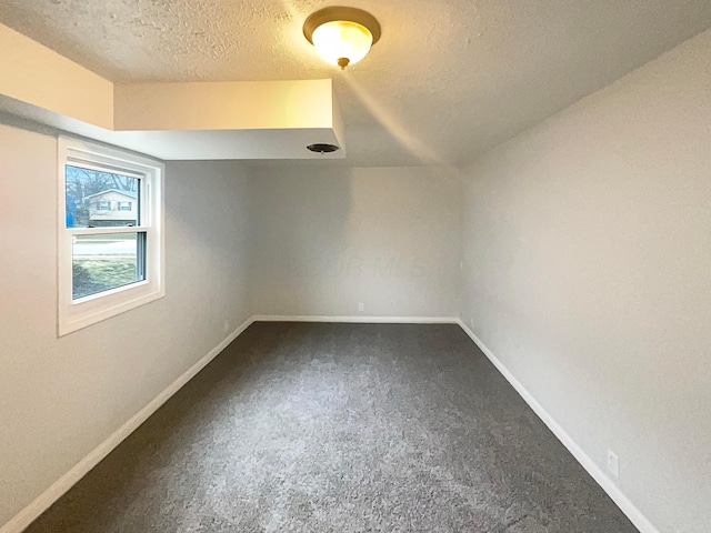 interior space with a textured ceiling, carpet floors, and baseboards