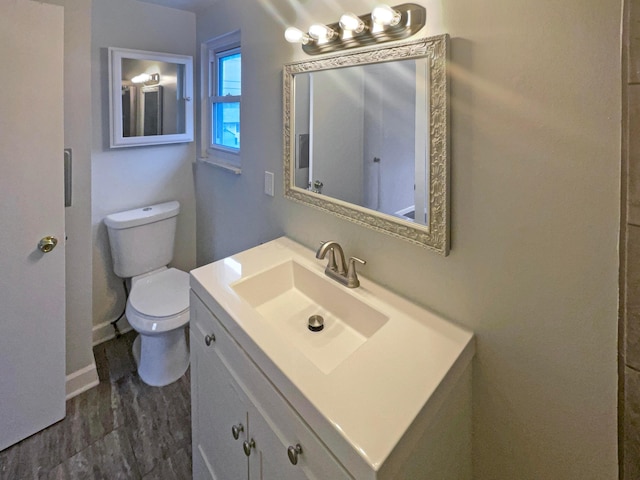 bathroom with baseboards, vanity, and toilet