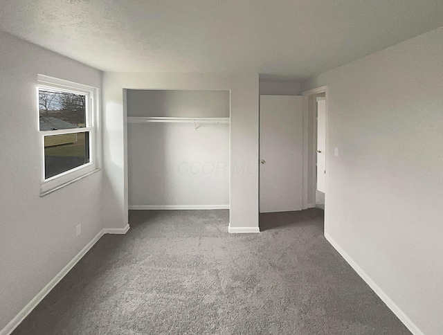 unfurnished bedroom featuring carpet floors, a textured ceiling, baseboards, and a closet