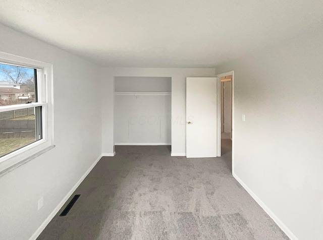 unfurnished bedroom featuring baseboards, a closet, visible vents, and carpet flooring