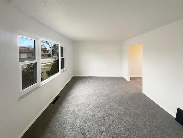 spare room with carpet, visible vents, and baseboards