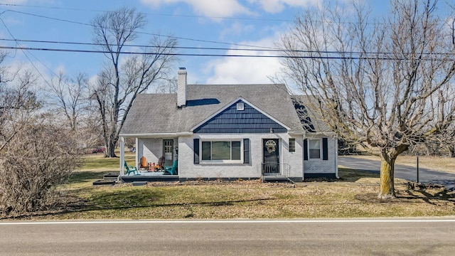 bungalow featuring a shingled roof, a front yard, a chimney, and brick siding