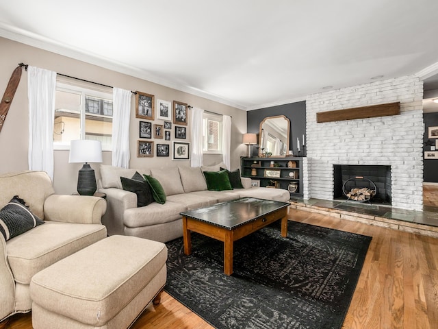 living area featuring a brick fireplace, ornamental molding, and wood finished floors