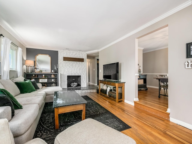 living room featuring ornamental molding, a fireplace, baseboards, and wood finished floors