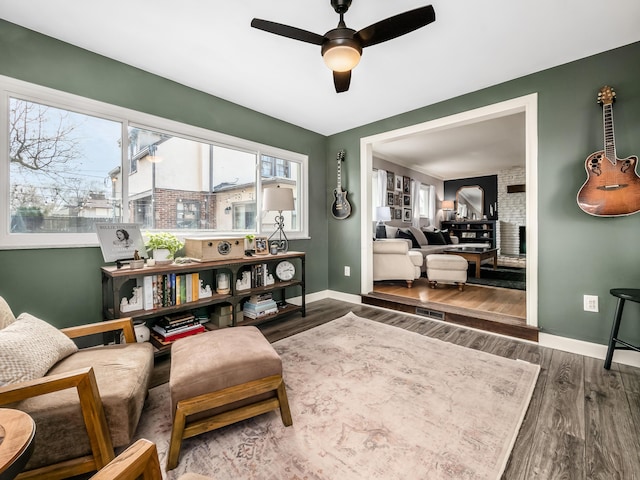 sitting room featuring a ceiling fan, baseboards, and wood finished floors