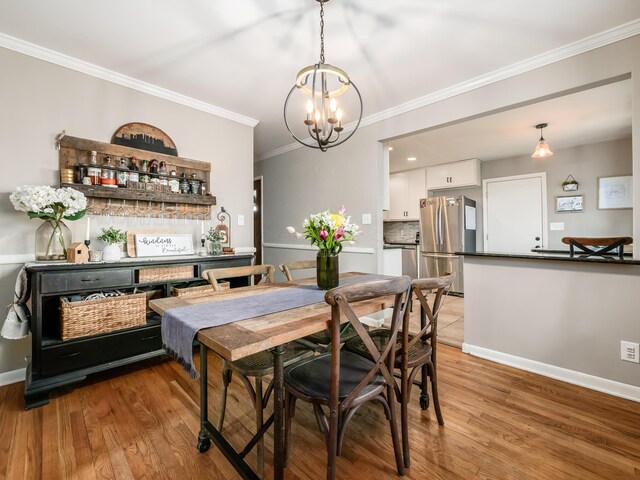 dining room featuring light wood-type flooring, an inviting chandelier, baseboards, and ornamental molding