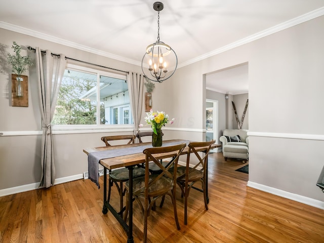 dining room with light wood finished floors, baseboards, a chandelier, and crown molding