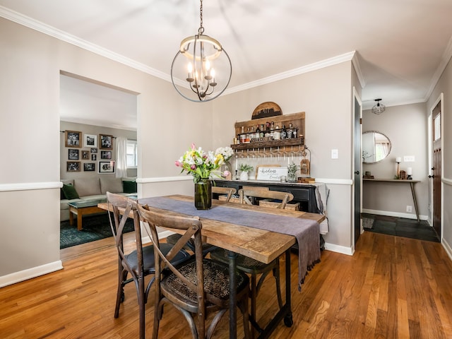 dining room with baseboards, ornamental molding, a chandelier, and wood finished floors