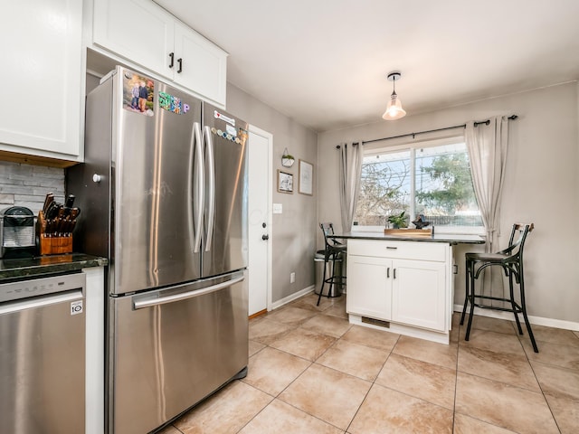 kitchen featuring stainless steel appliances, dark countertops, white cabinets, and light tile patterned floors