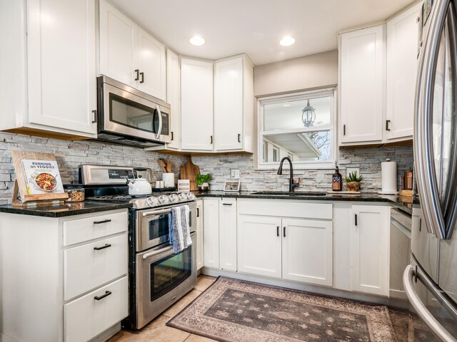 kitchen with recessed lighting, decorative backsplash, appliances with stainless steel finishes, white cabinets, and a sink