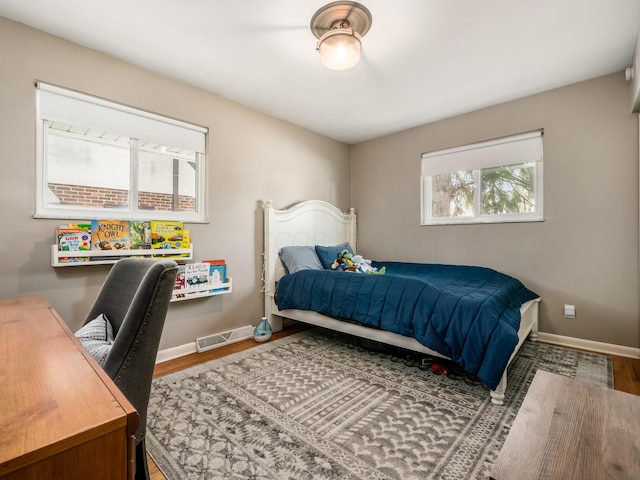 bedroom with visible vents, baseboards, and wood finished floors