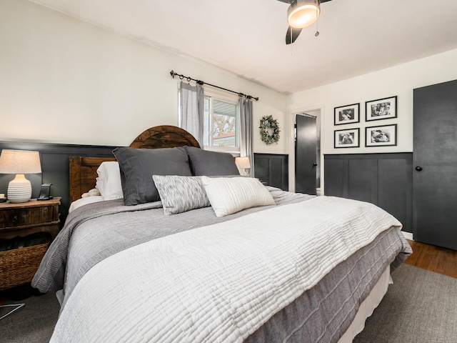 bedroom featuring ceiling fan, dark wood finished floors, and wainscoting