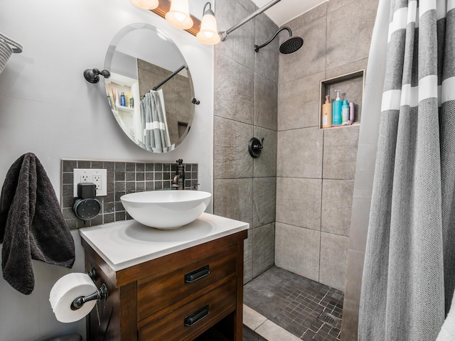 full bathroom with decorative backsplash, tiled shower, and vanity