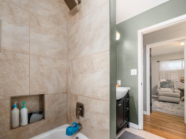 bathroom featuring tub / shower combination, vanity, baseboards, and wood finished floors