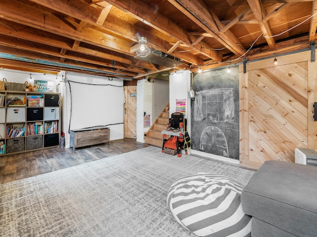 unfinished basement featuring a barn door, stairway, and wood finished floors