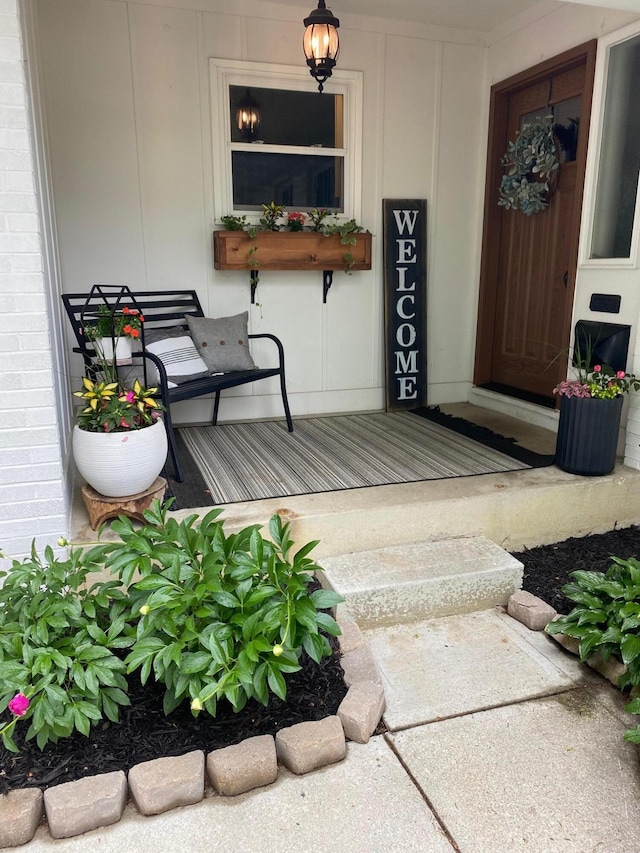 view of exterior entry with a porch and brick siding