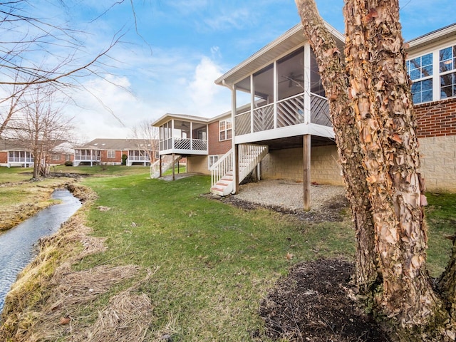 rear view of property with a yard, stairs, and a sunroom