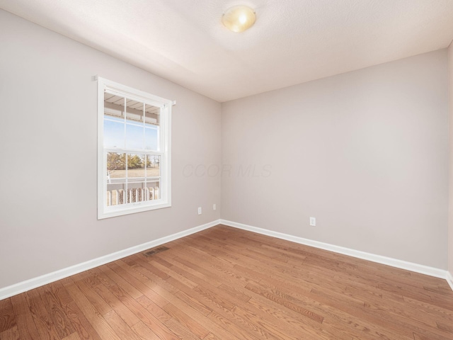 unfurnished room featuring light wood-style flooring, visible vents, and baseboards