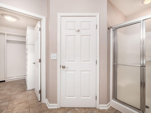 full bath featuring baseboards, a shower stall, and tile patterned flooring