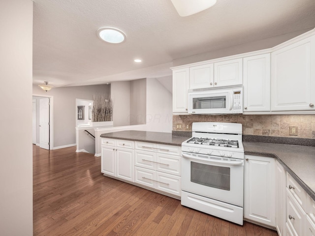 kitchen featuring dark countertops, decorative backsplash, white appliances, and wood finished floors