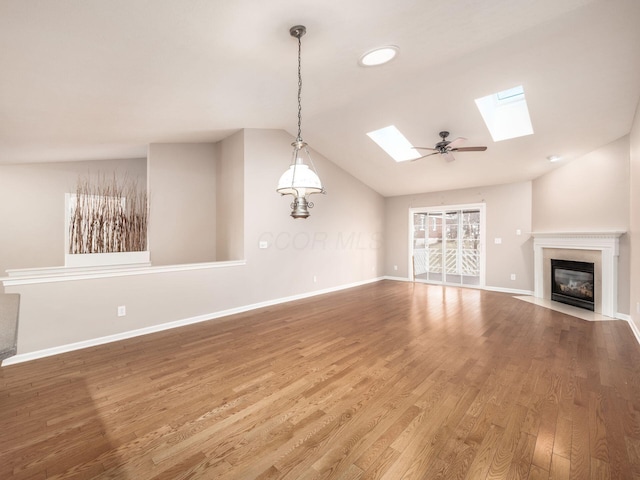 unfurnished living room with baseboards, lofted ceiling with skylight, wood finished floors, and a fireplace with flush hearth