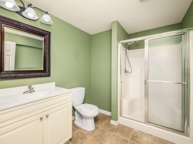 bathroom with toilet, a shower stall, tile patterned flooring, baseboards, and vanity