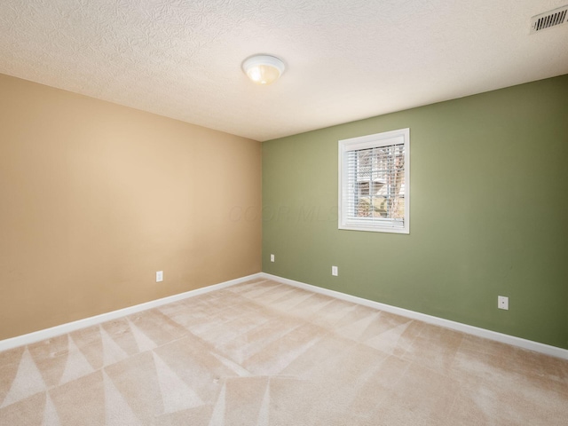 empty room featuring visible vents, baseboards, light colored carpet, and a textured ceiling