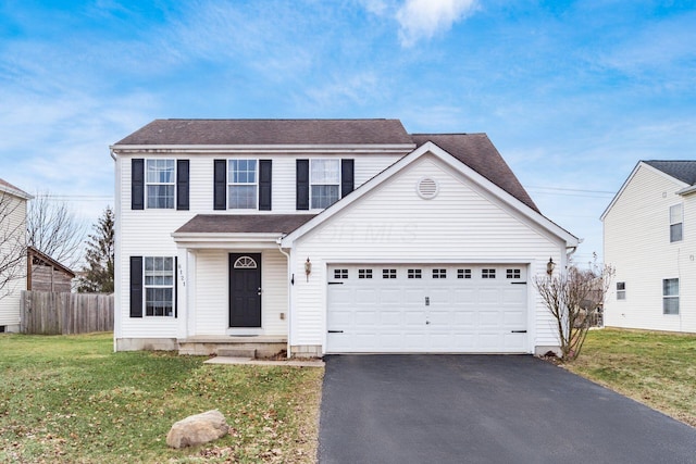 traditional-style house with a garage, fence, a front lawn, and aphalt driveway