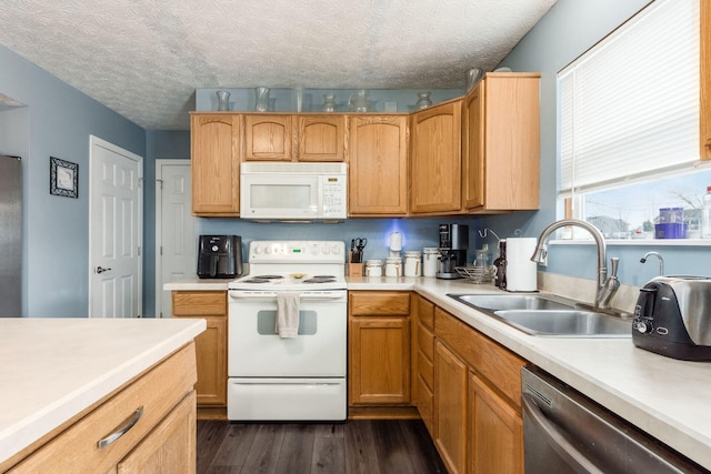 kitchen with white appliances, dark wood-style flooring, light countertops, a textured ceiling, and a sink