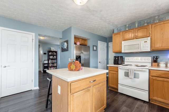 kitchen featuring a textured ceiling, white appliances, dark wood-type flooring, light countertops, and a kitchen bar