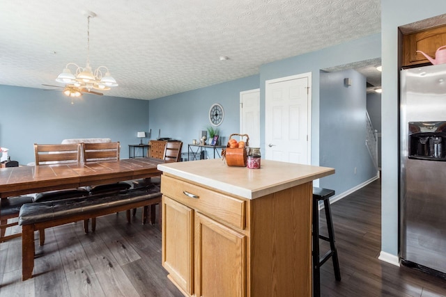 kitchen with stainless steel fridge with ice dispenser, a breakfast bar, dark wood-type flooring, a textured ceiling, and a notable chandelier