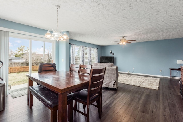 dining space featuring a textured ceiling, dark wood-type flooring, ceiling fan with notable chandelier, and baseboards