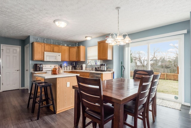 kitchen with a center island, light countertops, dark wood-type flooring, a sink, and white appliances