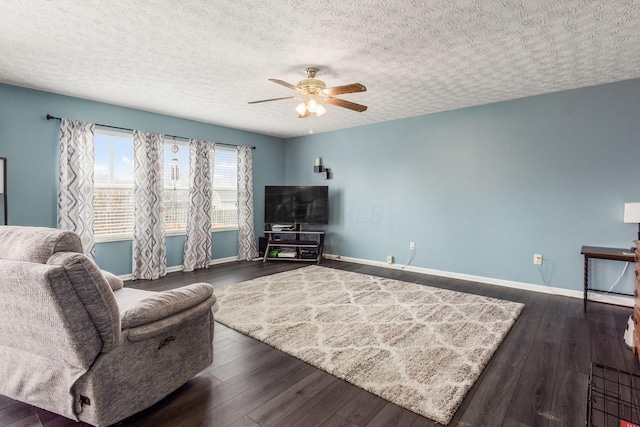 living room featuring a ceiling fan, dark wood finished floors, a textured ceiling, and baseboards