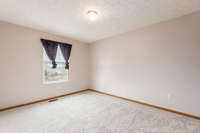 carpeted spare room featuring a textured ceiling, visible vents, and baseboards