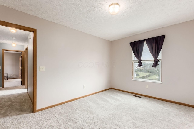 unfurnished room featuring carpet, a textured ceiling, visible vents, and baseboards