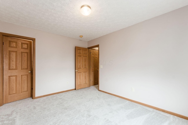 unfurnished bedroom with baseboards, a textured ceiling, and light colored carpet