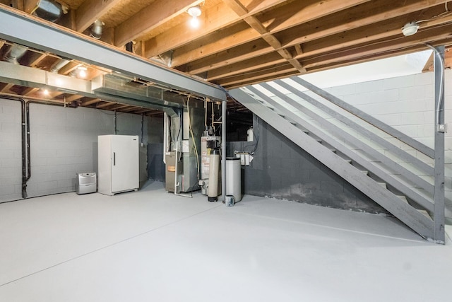 unfinished below grade area with gas water heater, freestanding refrigerator, and heating unit