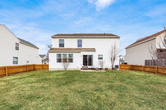 rear view of house featuring entry steps, a lawn, and a fenced backyard