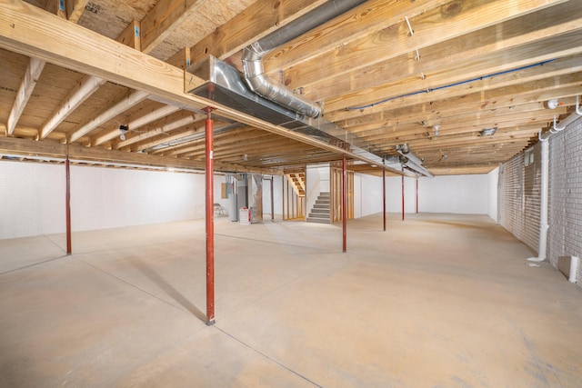 unfinished basement featuring stairs and brick wall